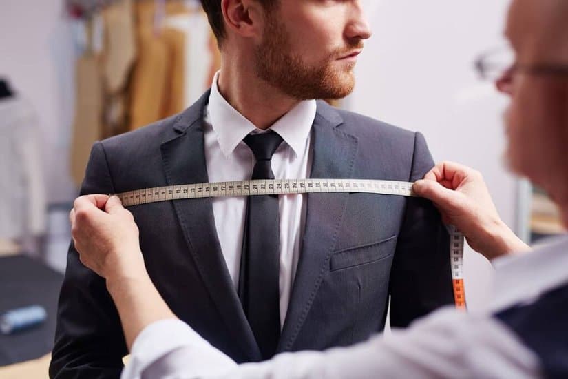 Tailor taking man's blazer measurement