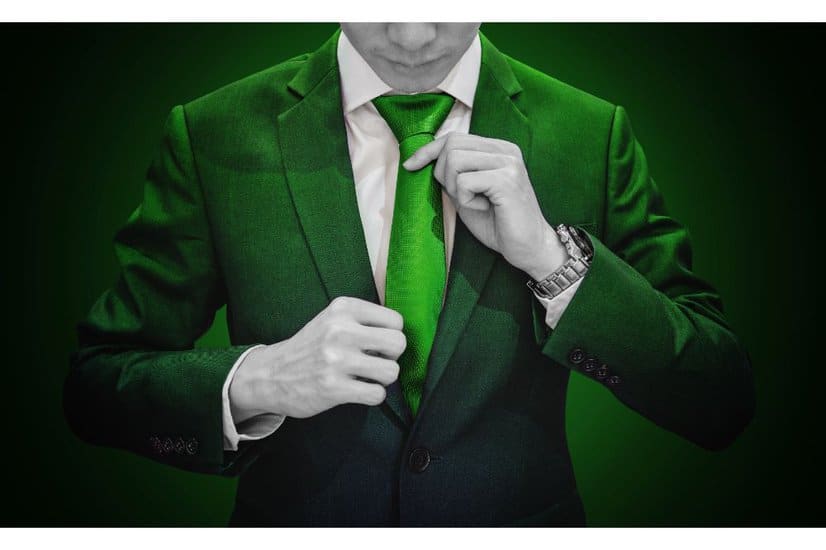 Businessman in green suit tying green necktie